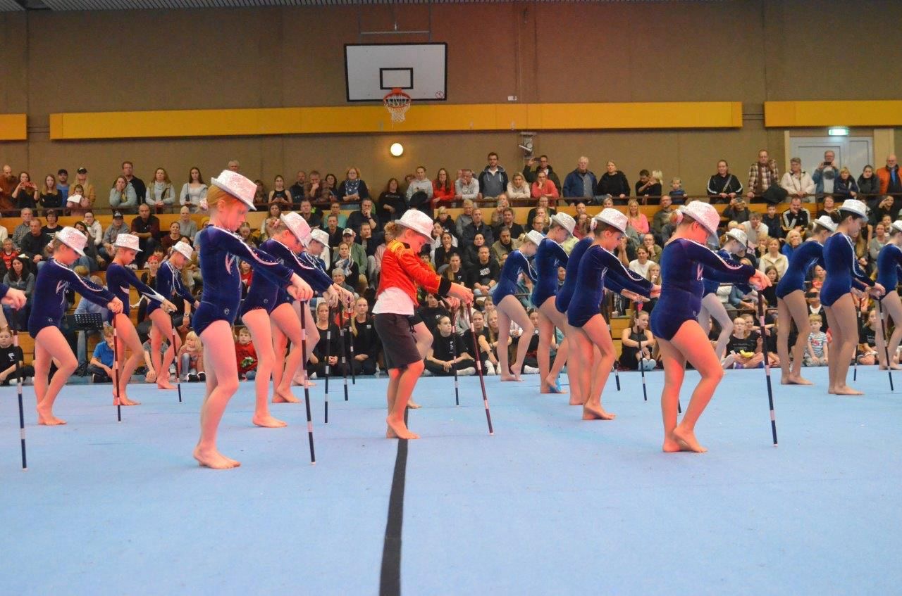 Konzentrierte Gruppen-Choreografie von Confianza – junge Performer:innen mit Hüten und Stöcken in einer Turnhalle vor Publikum
